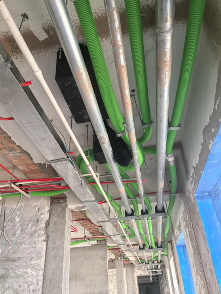 Real green branch ducts coordinated within an active ceiling-services zone before concealment.